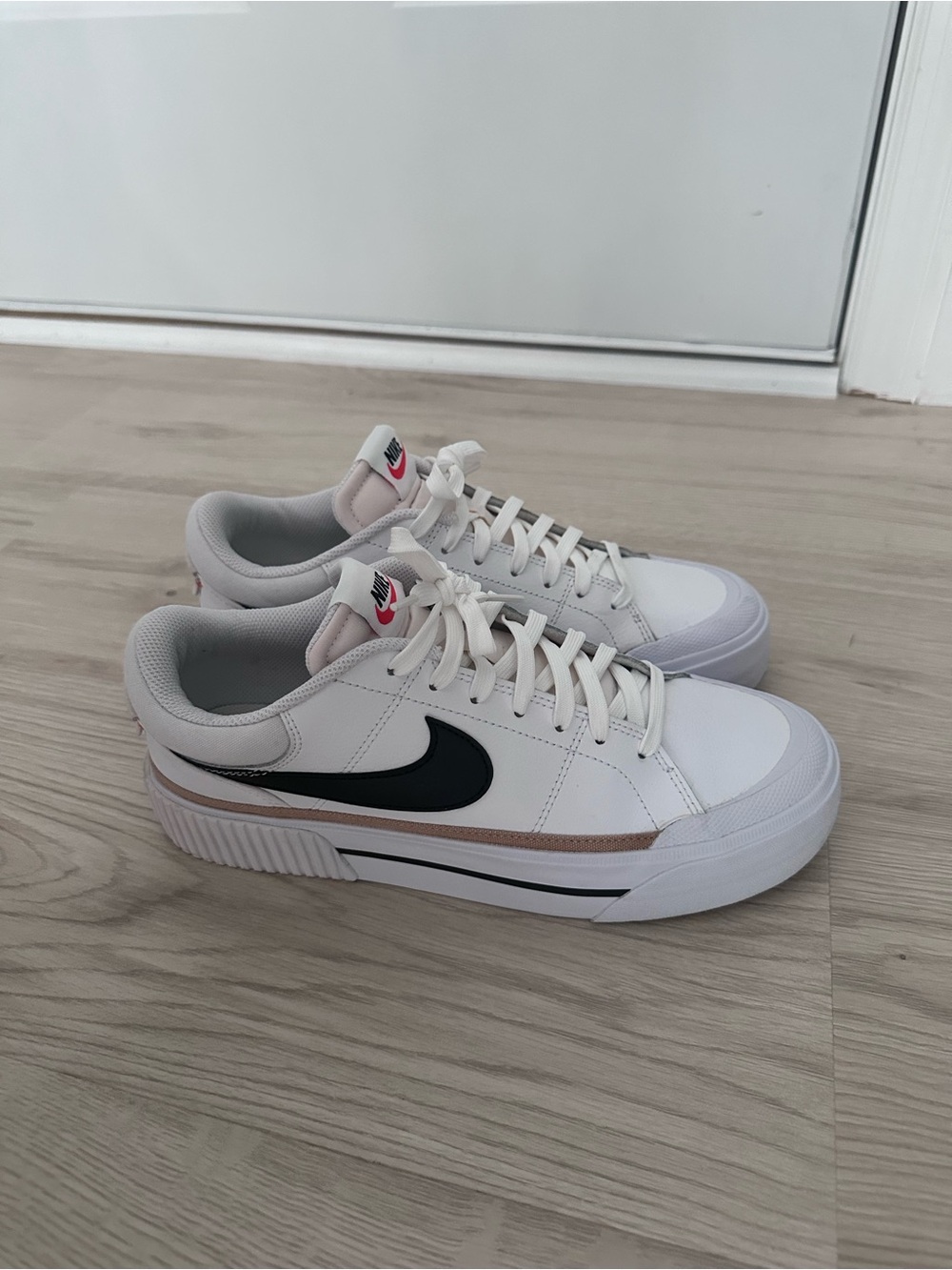 Women’s Nike White Sneakers with Black Swoosh and Rose Accent